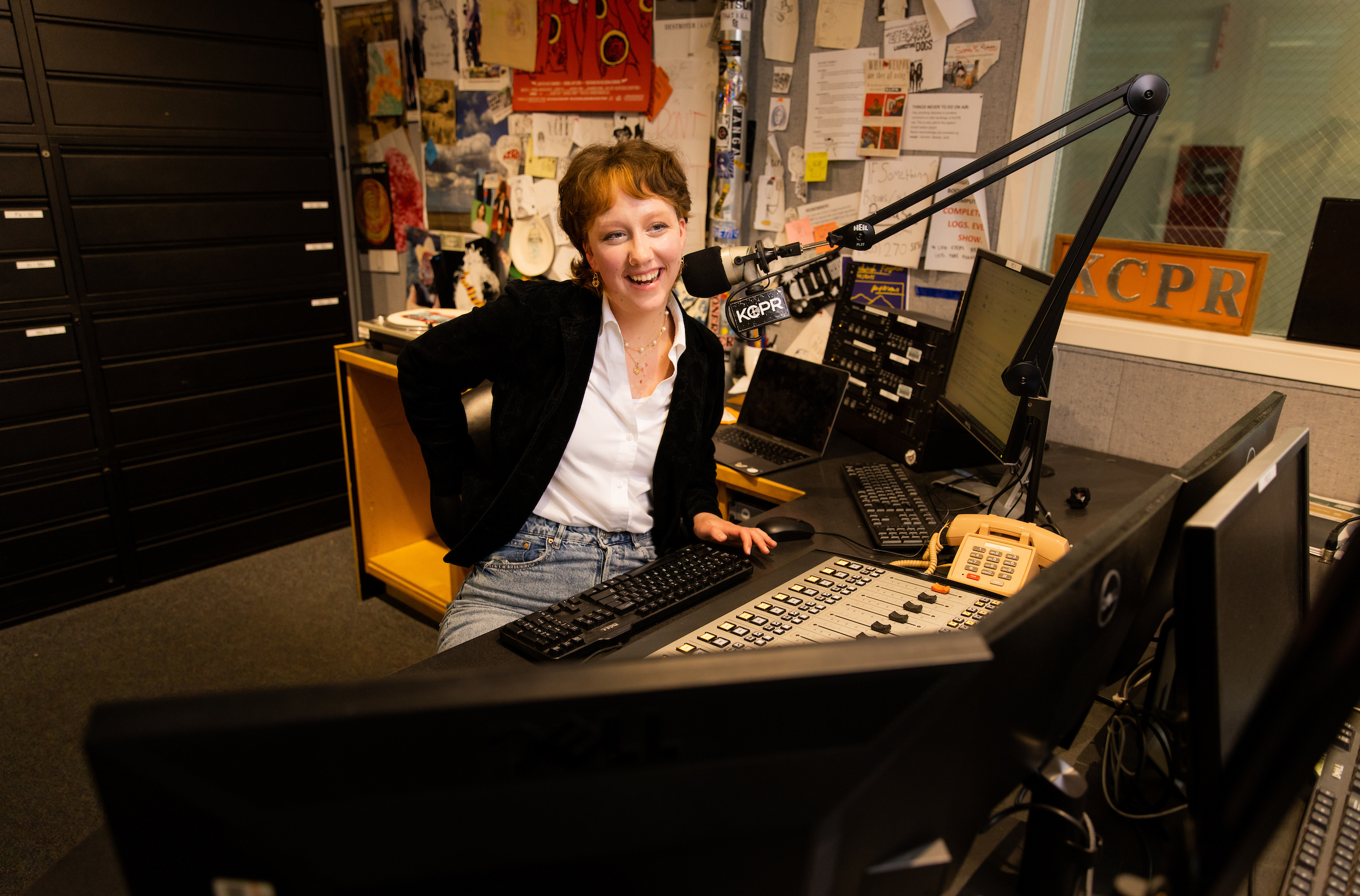Journalism student Zoe Boyd sits behind the DJ booth at KCPR, hosting her radio show.