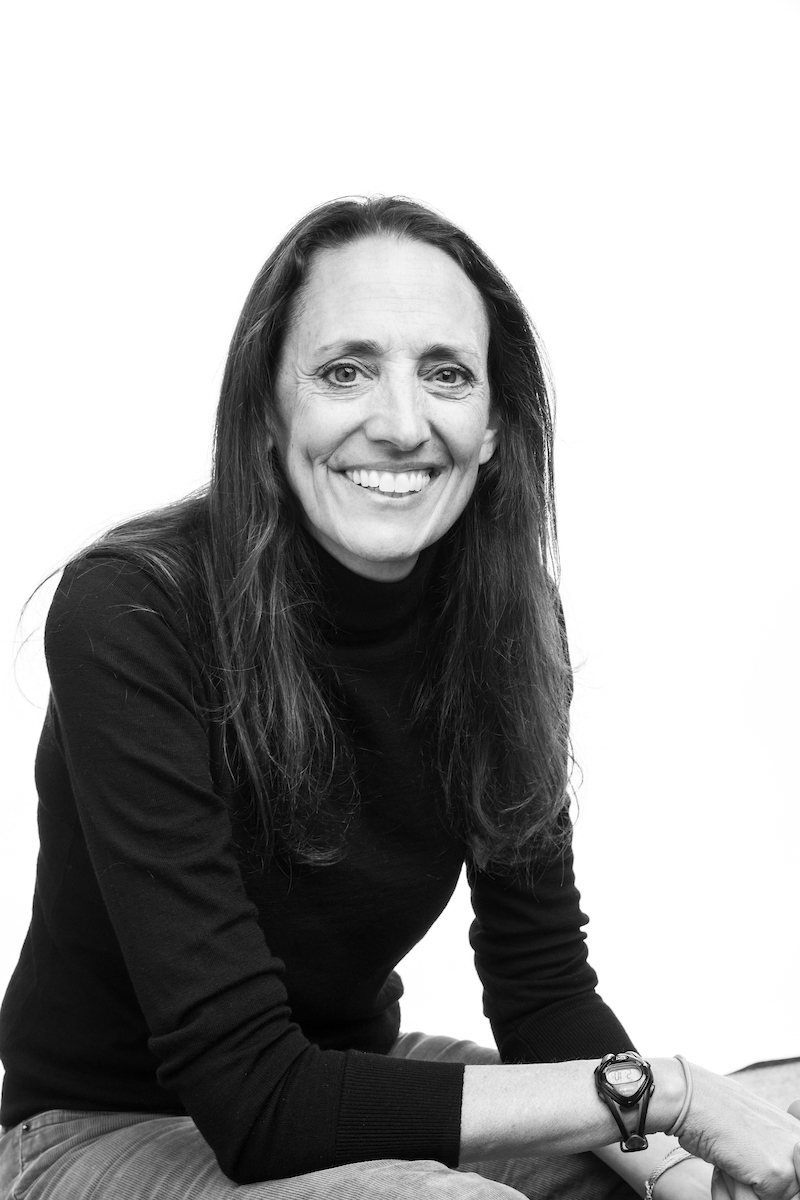 Professor Kira Abercromby seated for a black and white portrait, smiling in a dark sweater